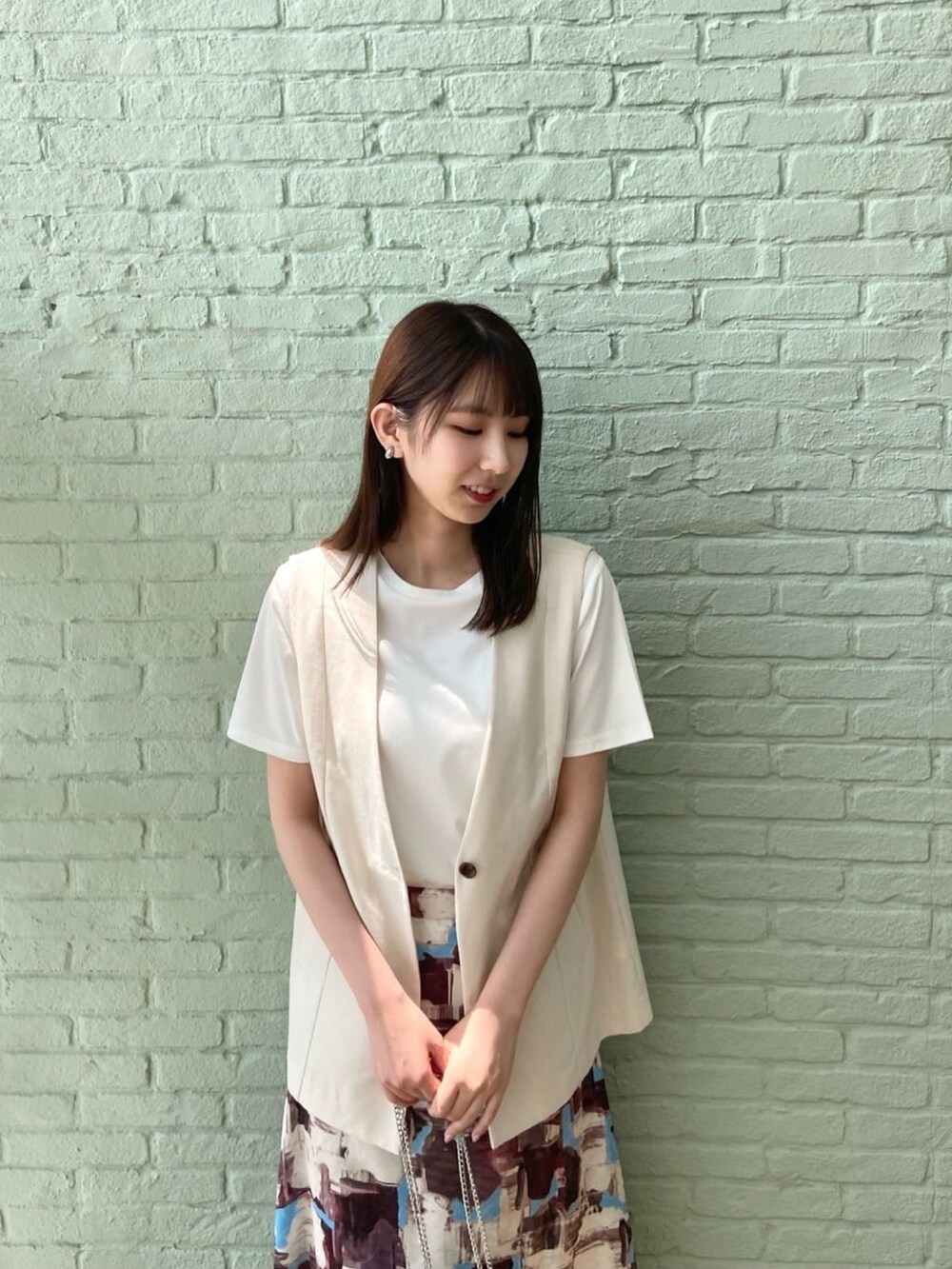 ベージュ系のベスト、ホワイト系のTシャツ/カットソー、レッド系のスカートを着用したレディースの夏コーディネートの7枚目の写真