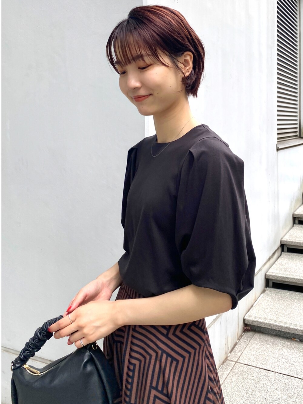 ブラウン系のスカート、ブラック系のTシャツ/カットソー、ブラック系のサンダルを着用したレディースの夏コーディネートの3枚目の写真