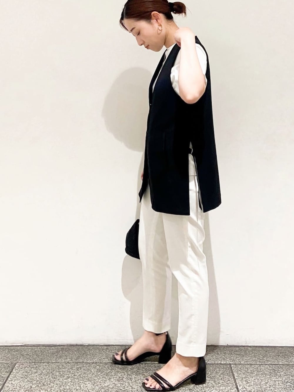 ホワイト系のTシャツ/カットソー、ブラック系のベスト、ブラック系のショルダーバッグを着用したレディースの夏コーディネートの5枚目の写真
