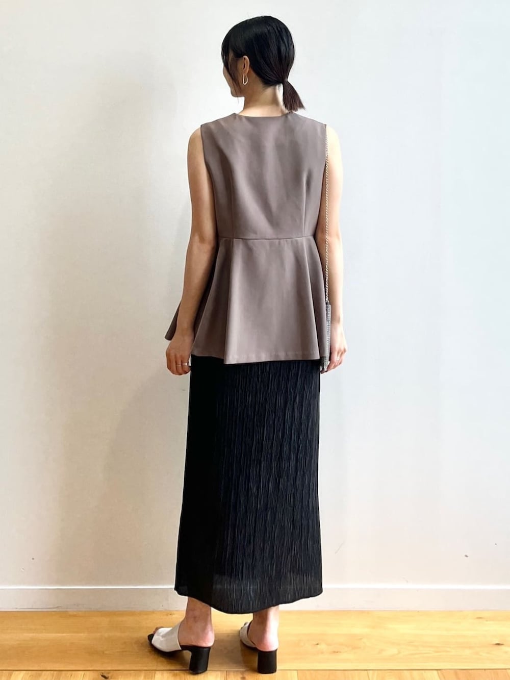 ホワイト系のタンクトップ、ホワイト系のサンダル、ブラウン系のベストを着用したレディースの夏コーディネートの3枚目の写真