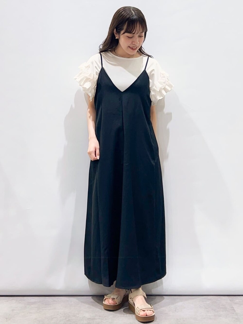 ブラック系のワンピース、ベージュ系のサンダル、ホワイト系のTシャツ/カットソーを着用したレディースの夏コーディネートの2枚目の写真