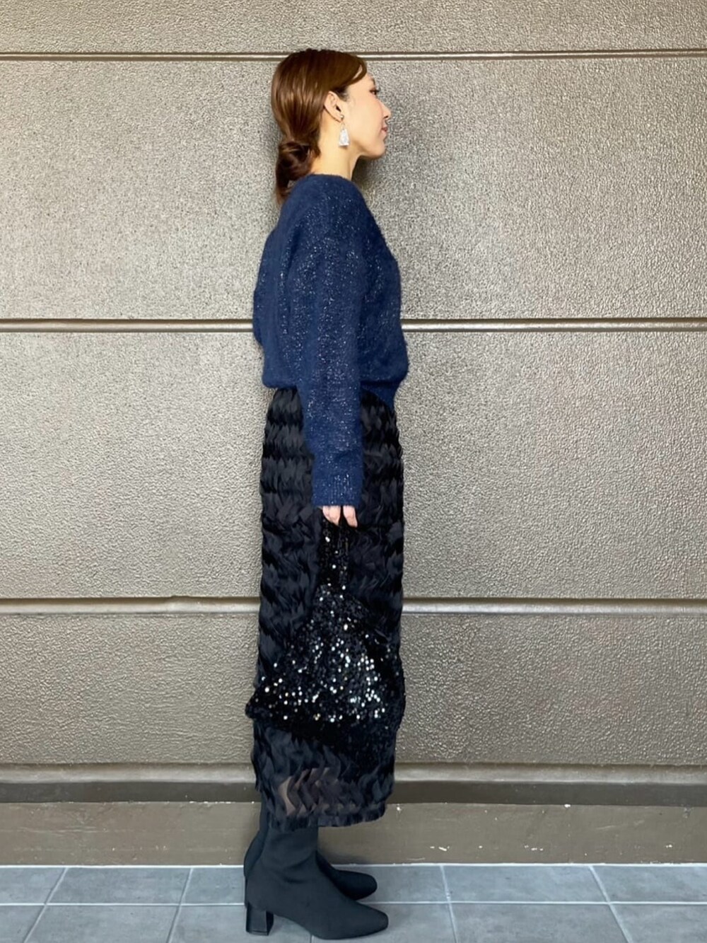 ブラック系のスカート、ブルー系のニット/セーター、ブラック系のブーツを着用したレディースの秋コーディネートの3枚目の写真