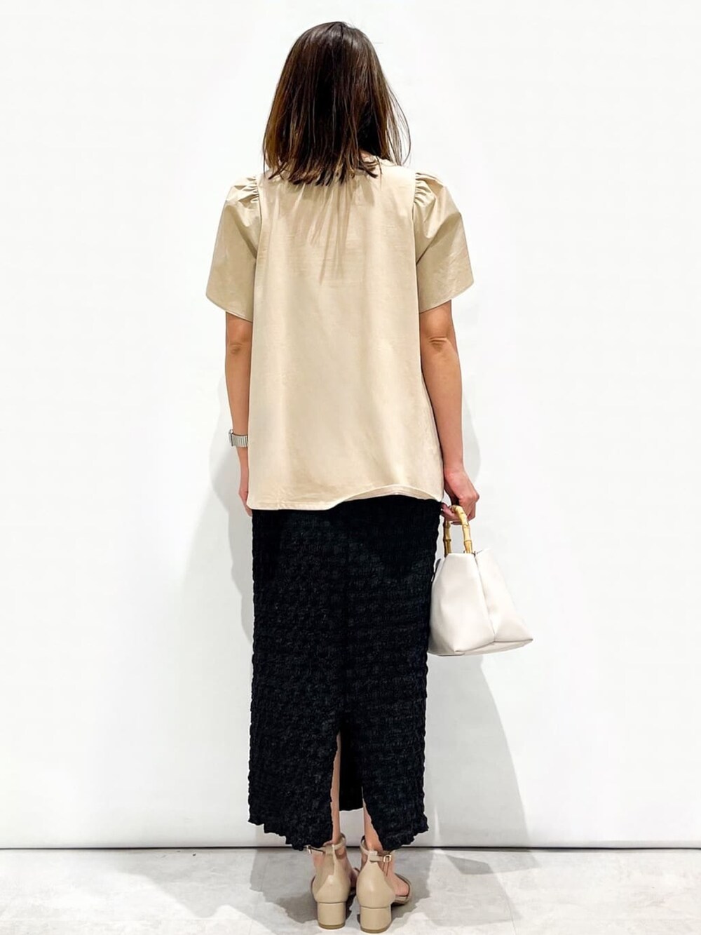 ベージュ系のTシャツ/カットソー、ブラック系のスカート、ホワイト系のショルダーバッグを着用したレディースの春コーディネートの7枚目の写真