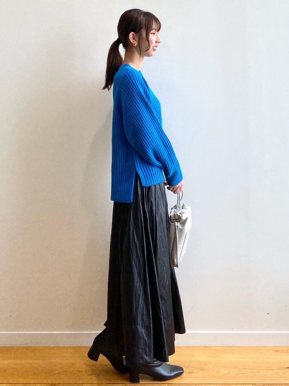 ブルー系のニット/セーター、ブラック系のスカート、ブラック系のブーツを着用したレディースの秋コーディネートの3枚目の写真