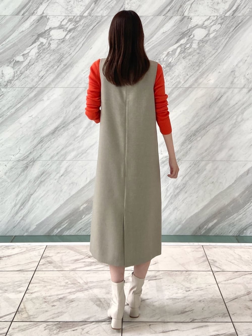 オレンジ系のニット/セーター、ベージュ系のワンピース、ホワイト系のブーツを着用したレディースの秋コーディネートの4枚目の写真