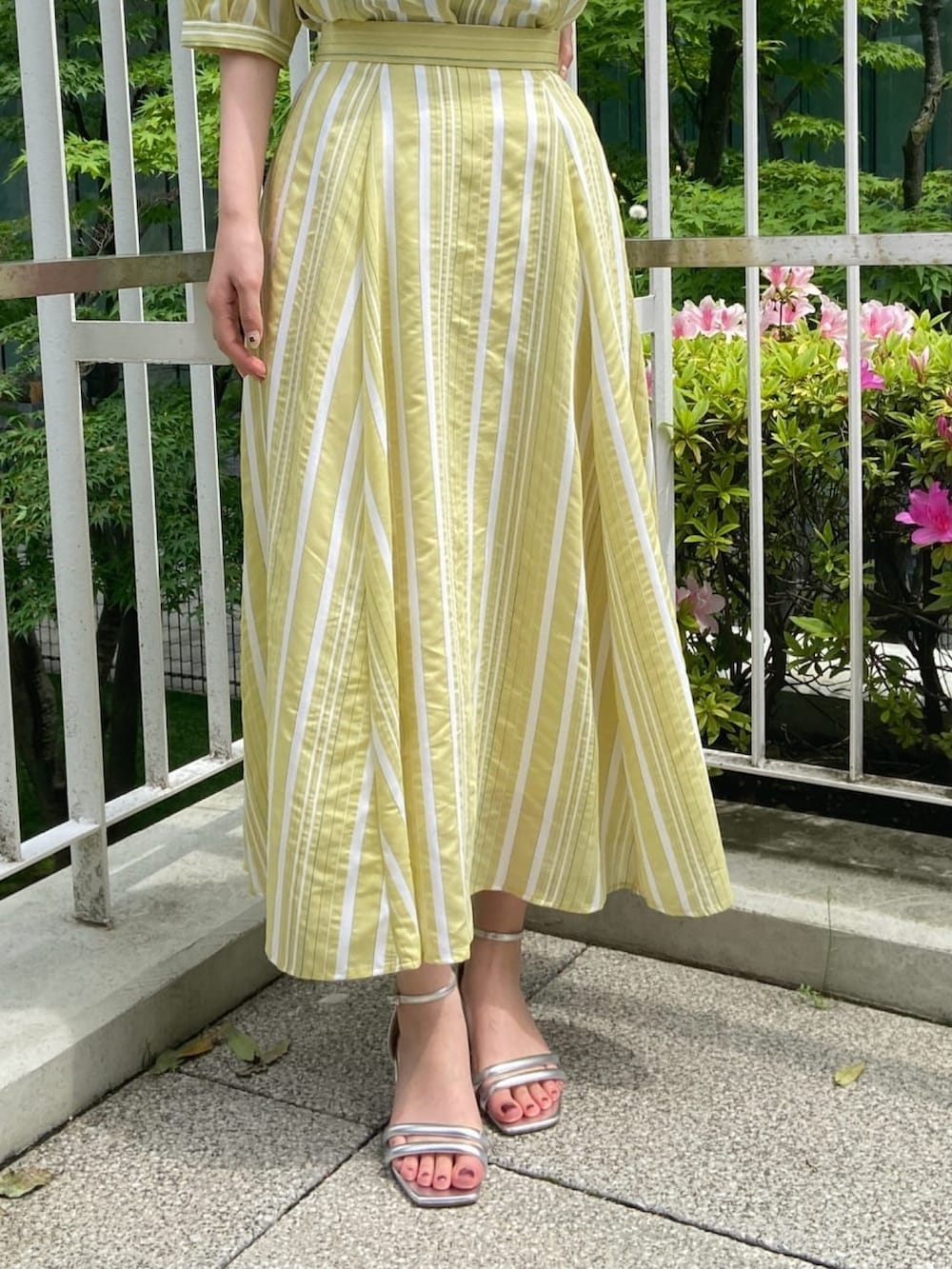 イエロー系のシャツ/ブラウス、イエロー系のスカート、シルバー系のサンダルを着用したレディースの春コーディネートの10枚目の写真