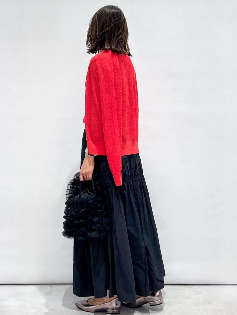 レッド系のカーディガン/ボレロ、レッド系のニット/セーター、ブラック系のスカートを着用したレディースの夏コーディネートの4枚目の写真