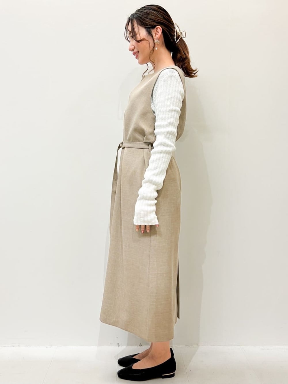 ベージュ系のワンピース、ホワイト系のニット/セーター、ブラック系のトートバッグを着用したレディースの春コーディネートの2枚目の写真