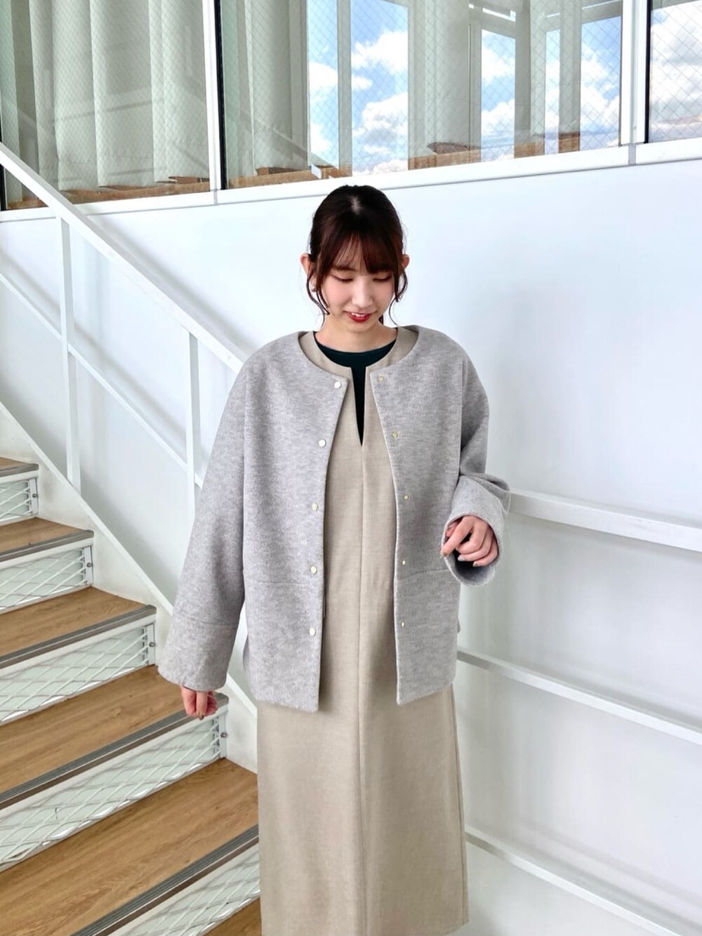 グレー系のノーカラーコート、ベージュ系のワンピース、ホワイト系のブーツを着用したレディースの秋コーディネートの6枚目の写真