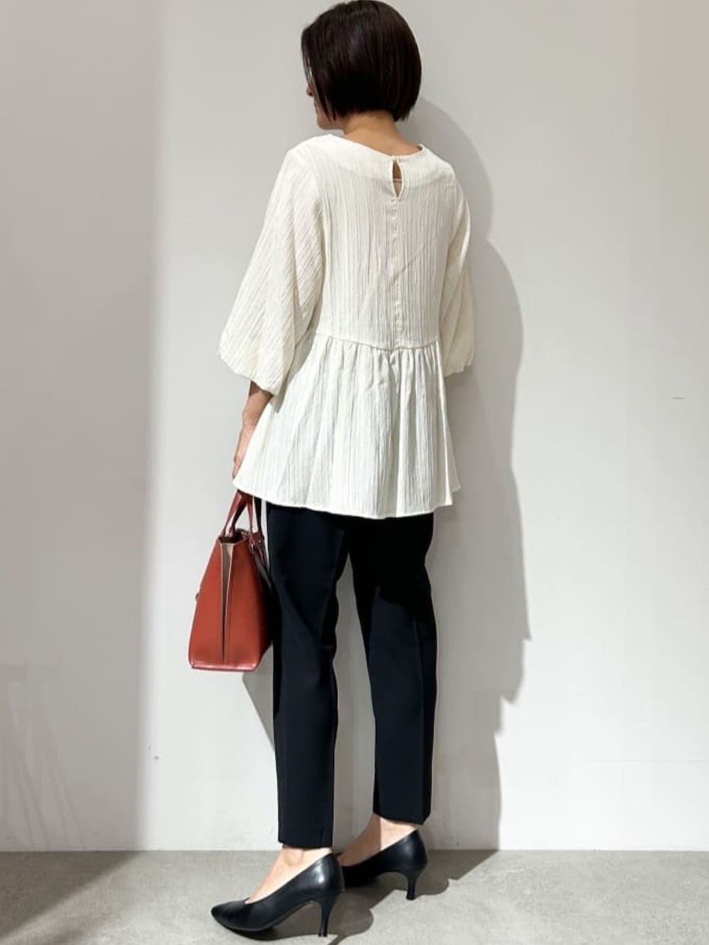 ホワイト系のシャツ/ブラウス、ブラック系のパンプス、レッド系のトートバッグを着用したレディースの夏コーディネートの2枚目の写真