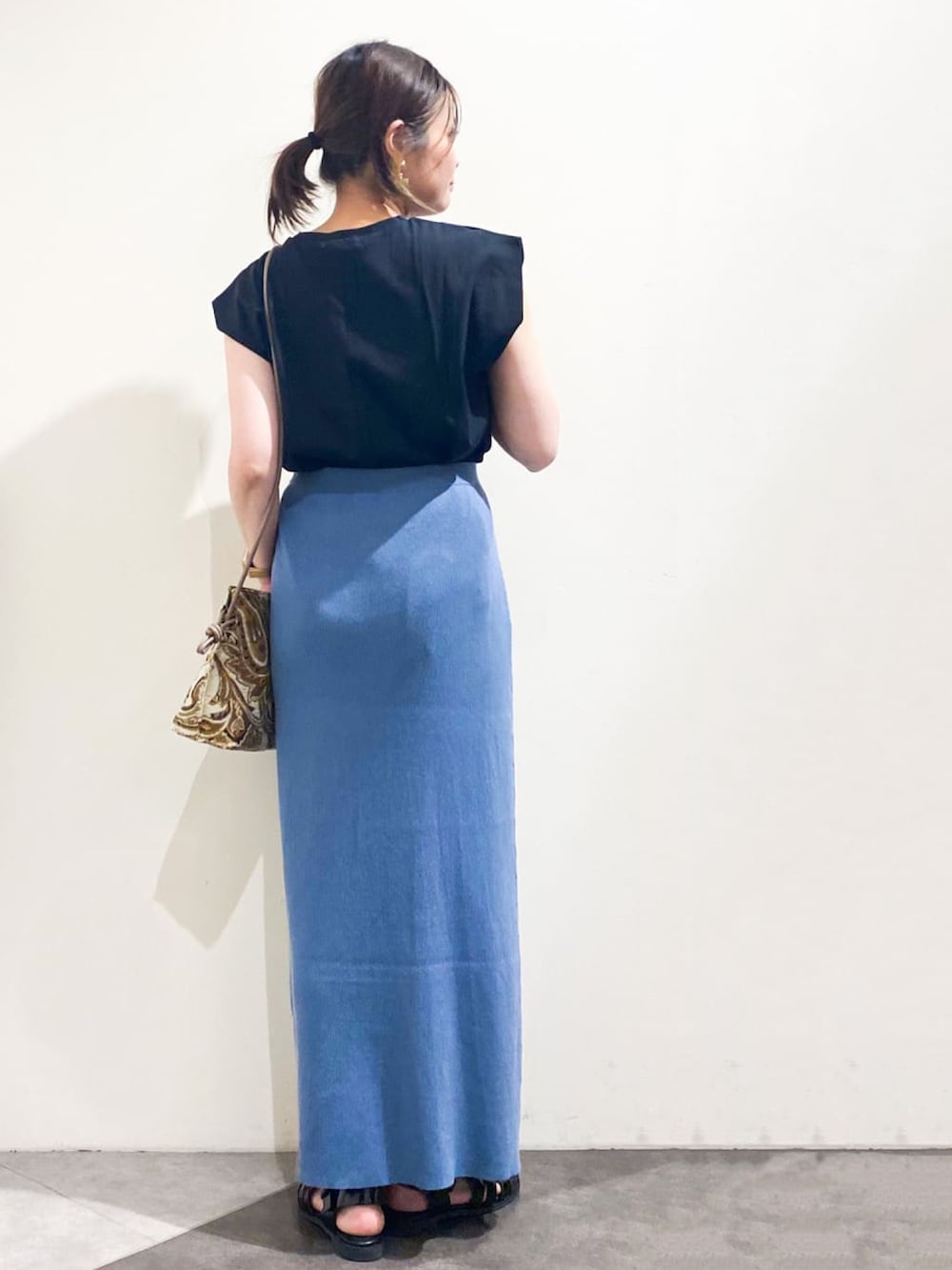 ブラック系のTシャツ/カットソー、ブルー系のスカート、ベージュ系のショルダーバッグを着用したレディースの夏コーディネートの3枚目の写真