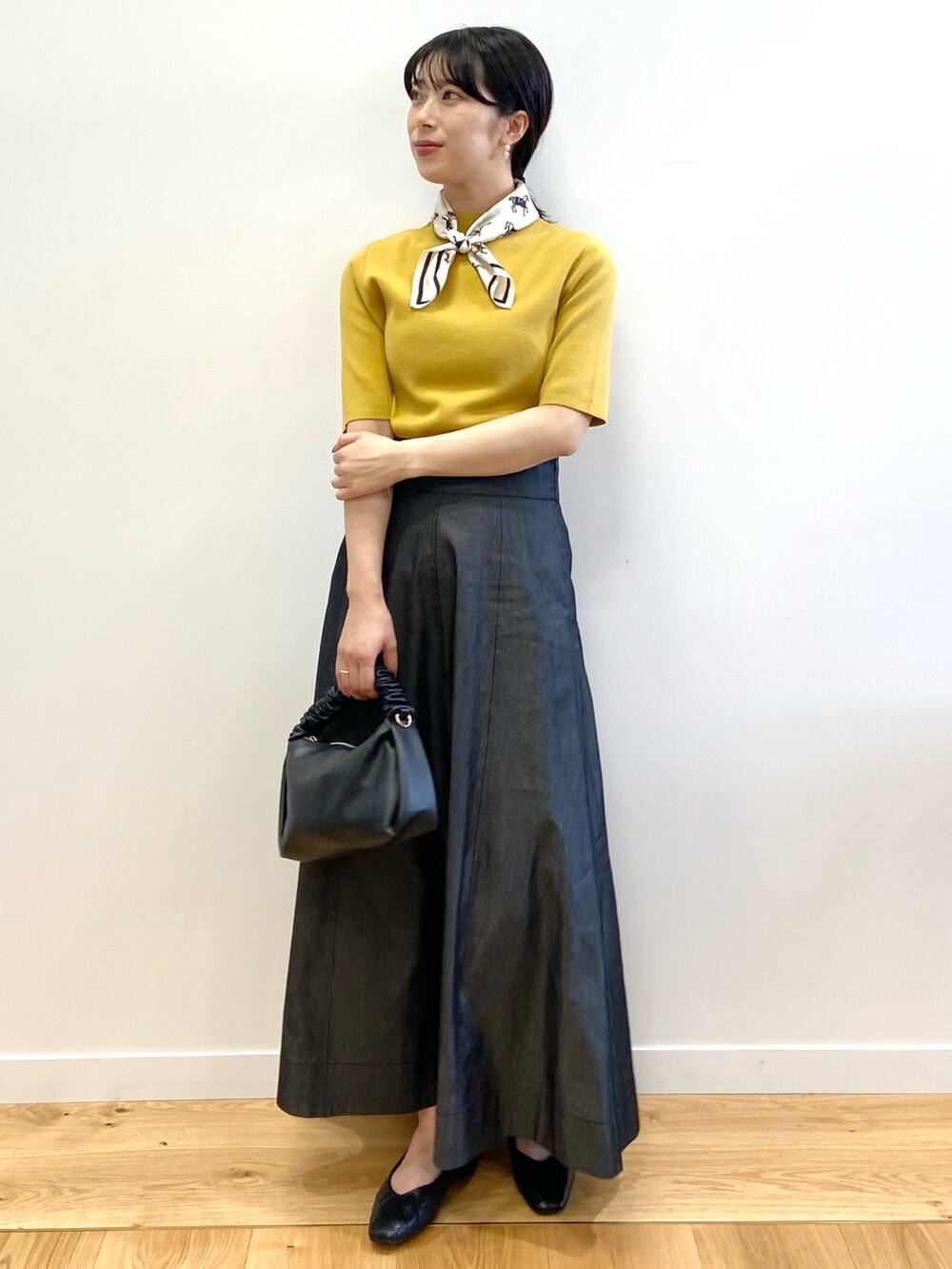 イエロー系のニット/セーター、その他のスカート、ブラック系のショルダーバッグを着用したレディースの夏コーディネートの2枚目の写真