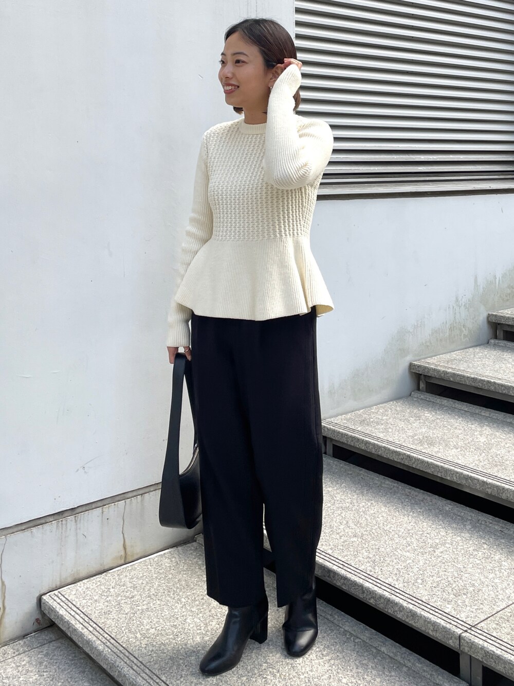 ブルー系のチェスターコート、ホワイト系のニット/セーター、ブラック系のその他パンツを着用したレディースの冬コーディネートの4枚目の写真