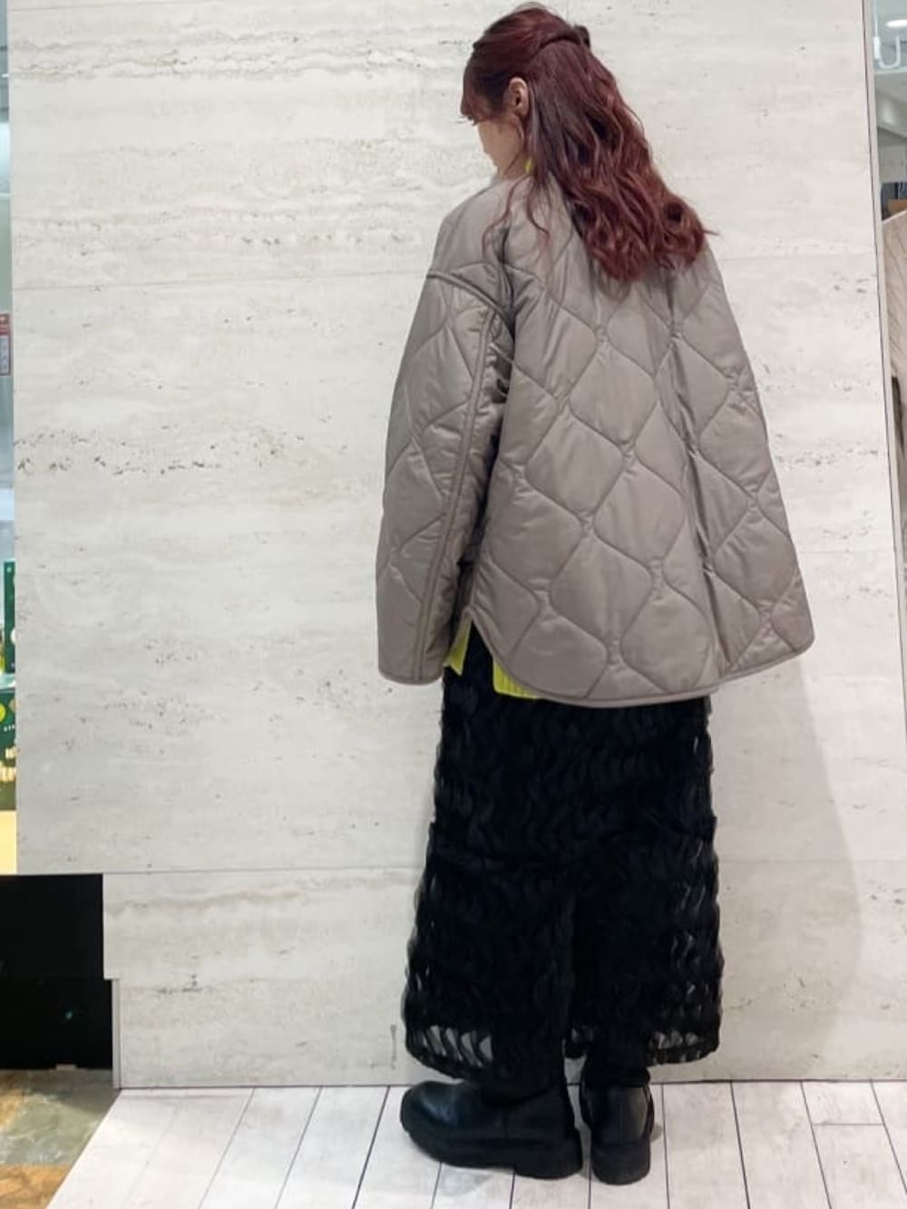 ブラウン系のノーカラーコート、イエロー系のニット/セーター、ブラック系のスカートを着用したレディースの冬コーディネートの5枚目の写真