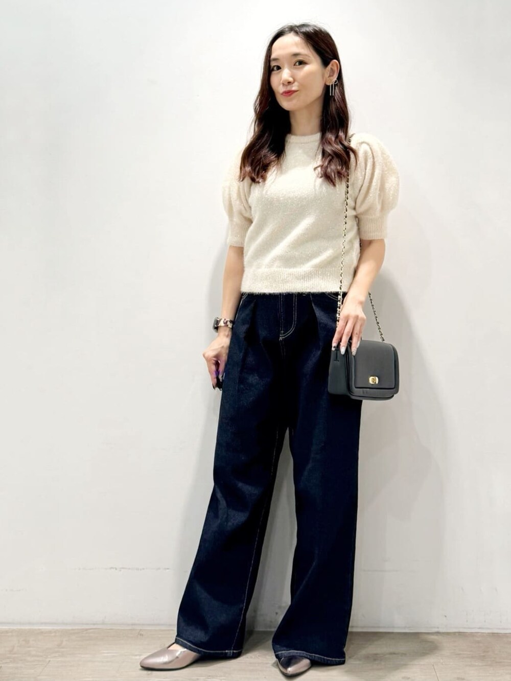 ベージュ系のニット/セーター、ブラック系のショルダーバッグ、ブルー系のデニムパンツを着用したレディースの秋コーディネートの3枚目の写真
