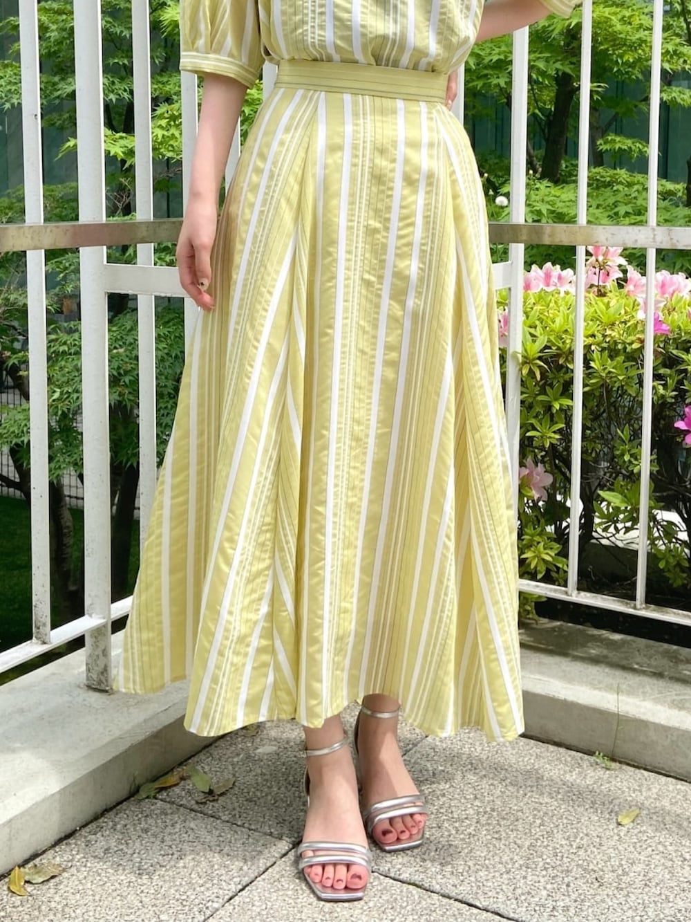 イエロー系のシャツ/ブラウス、イエロー系のスカート、シルバー系のサンダルを着用したレディースの春コーディネートの9枚目の写真