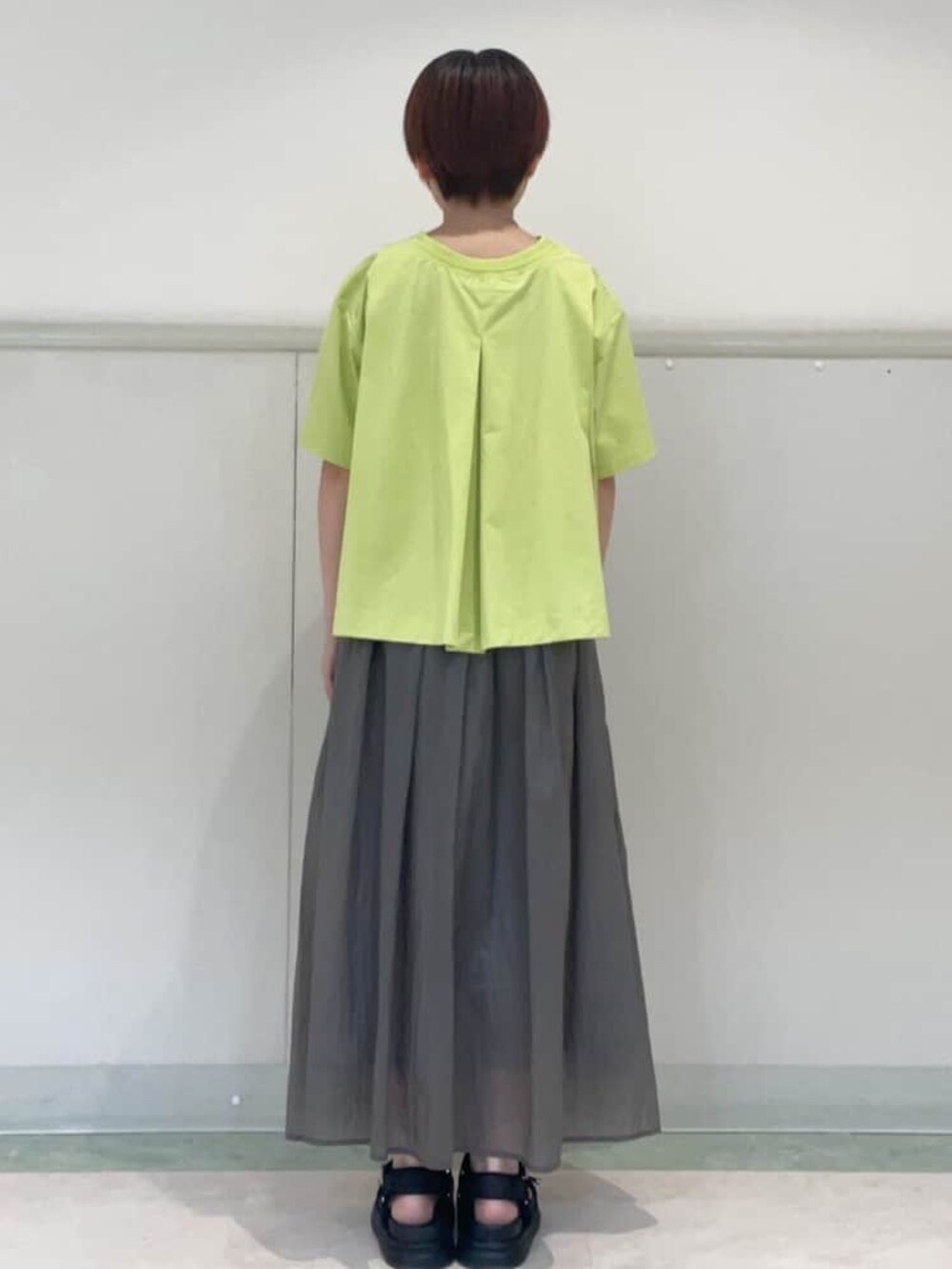 グレー系のスカート、ブラック系のサンダル、グリーン系のTシャツ/カットソーを着用したレディースの春コーディネートの4枚目の写真
