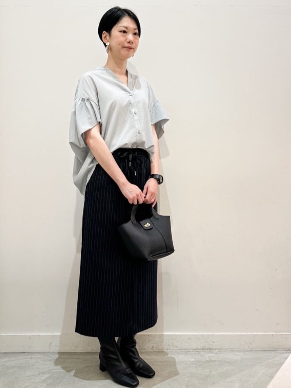 グリーン系のシャツ/ブラウス、ブルー系のスカート、ブラック系のトートバッグを着用したレディースの夏コーディネートの2枚目の写真