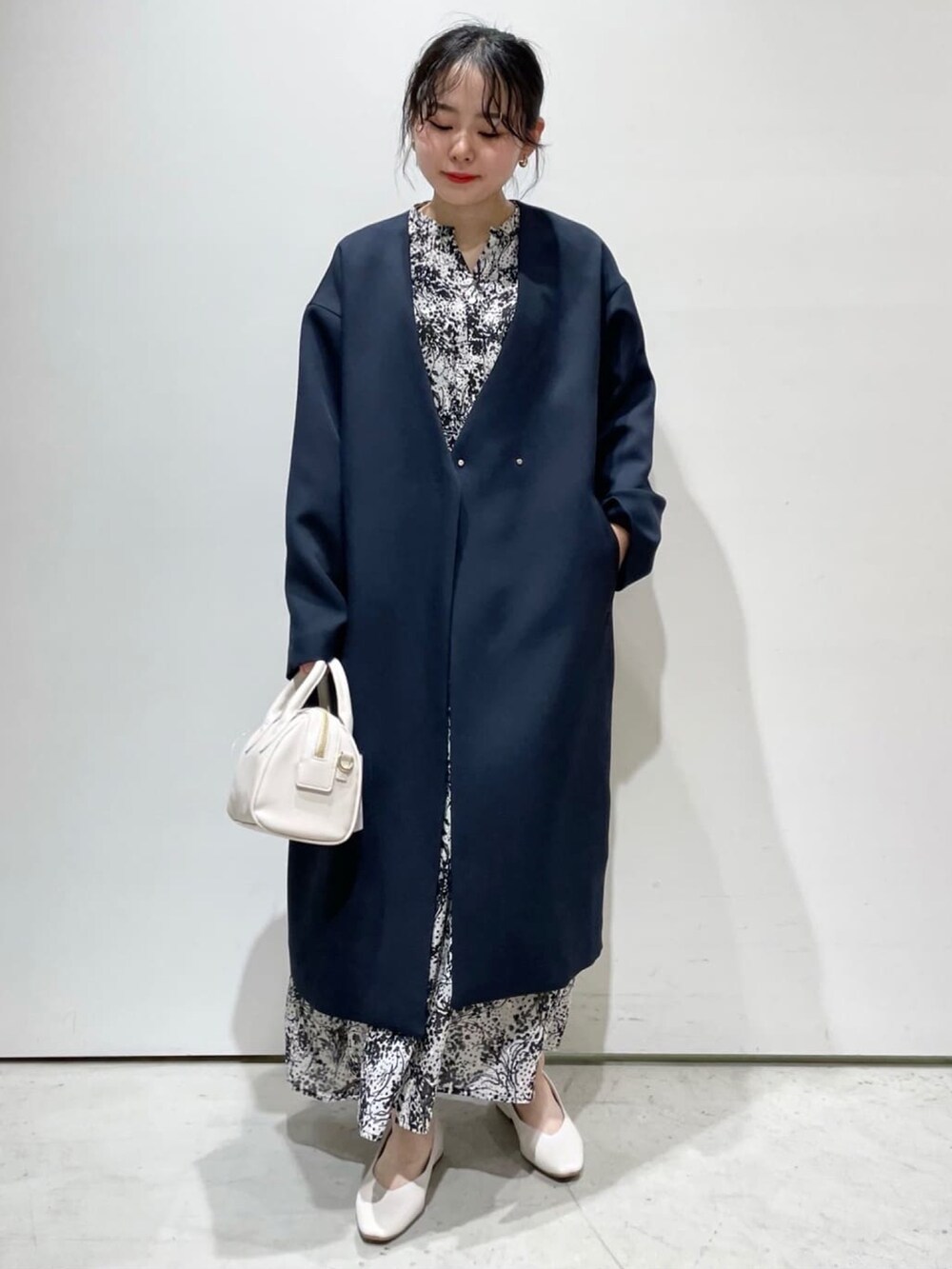 ブルー系のノーカラーコート、ブラック系のワンピース、ホワイト系のパンプスを着用したレディースの春コーディネートの2枚目の写真