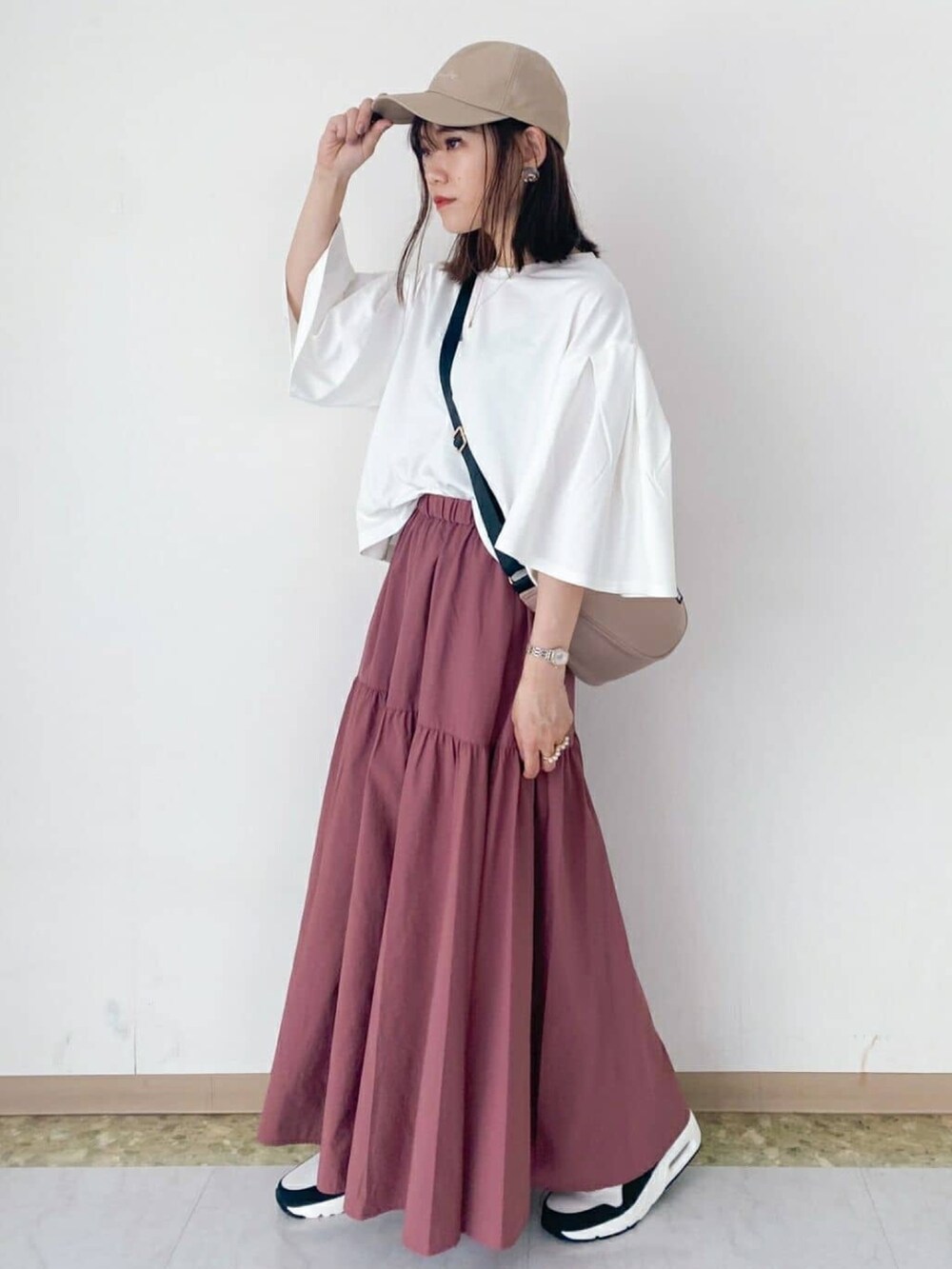 ピンク系のスカート、ホワイト系のTシャツ/カットソー、ベージュ系のショルダーバッグを着用したレディースの秋コーディネートの2枚目の写真