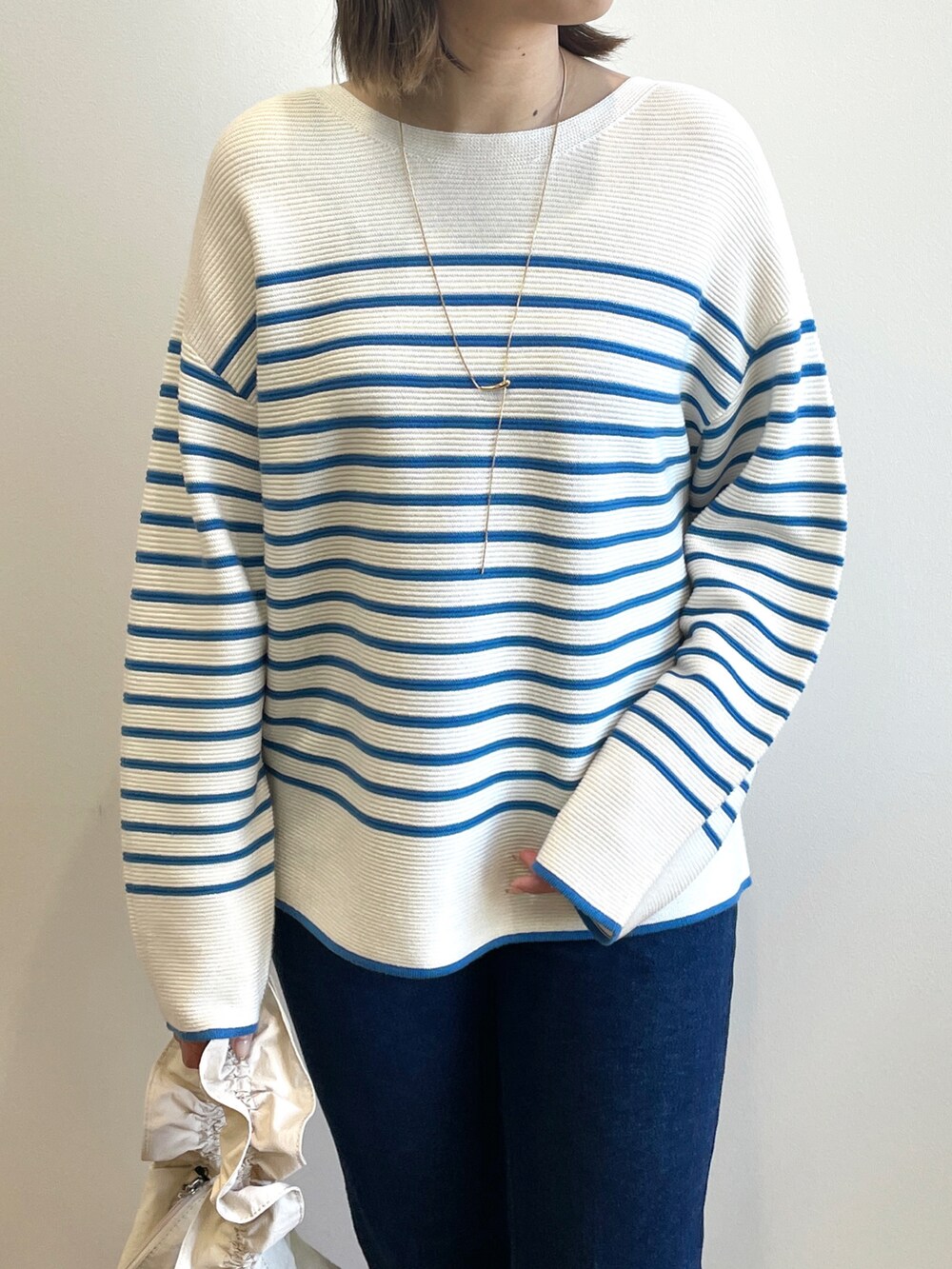 ブルー系のニット/セーター、ブルー系のデニムパンツ、ホワイト系のブーツを着用したレディースの冬コーディネートの4枚目の写真