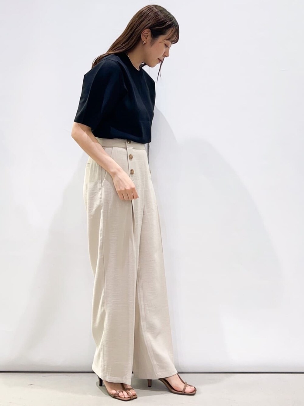 ブラック系のニット/セーター、ベージュ系のその他パンツ、ブラウン系のサンダルを着用したレディースの春コーディネートの2枚目の写真