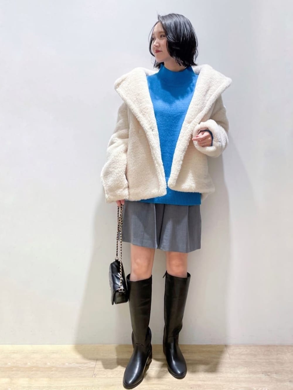 ブルー系のニット/セーター、グレー系のその他パンツ、ブラック系のブーツを着用したレディースの冬コーディネートの2枚目の写真