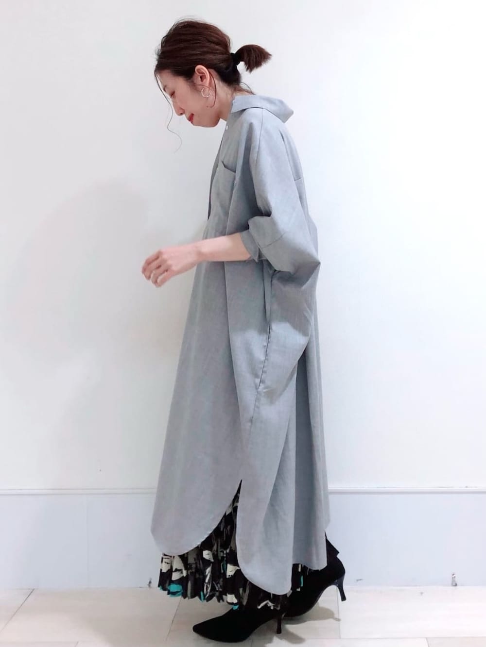 グレー系のワンピース、ブラック系のスカート、ブラック系のブーツを着用したレディースの秋コーディネートの2枚目の写真