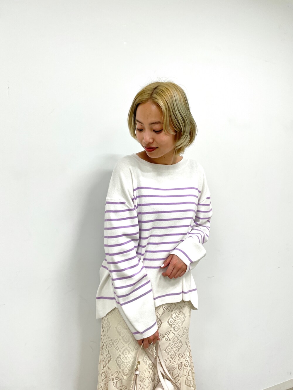 パープル系のニット/セーター、ホワイト系のスカート、ホワイト系のショルダーバッグを着用したレディースの冬コーディネートの3枚目の写真