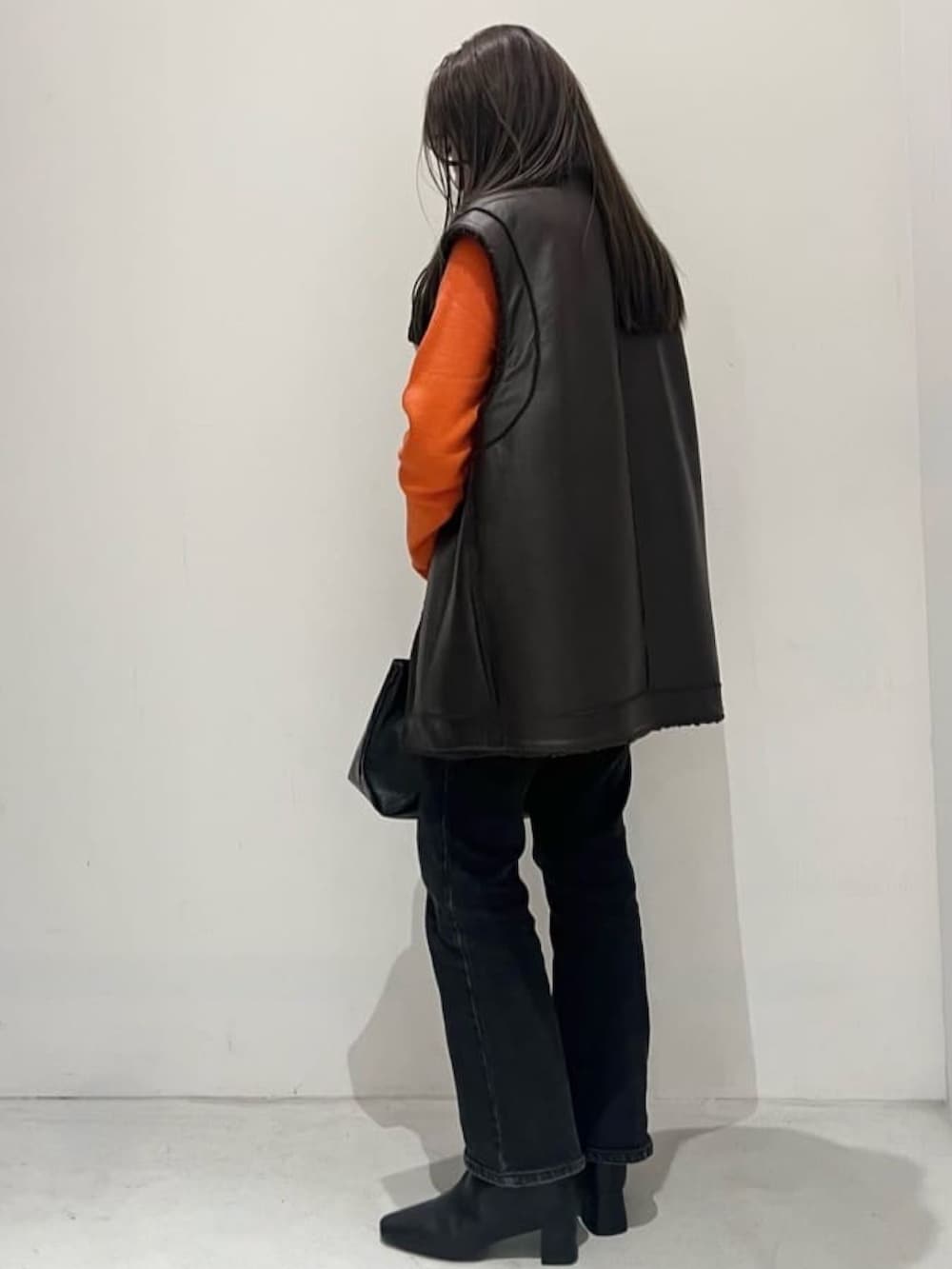 ブラック系のスニーカー、ブラック系のトートバッグ、ブラウン系のベストを着用したレディースの秋コーディネートの2枚目の写真