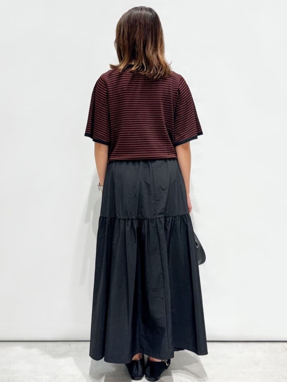 ブラック系のスカート、ブラウン系のニット/セーター、ブラック系のショルダーバッグを着用したレディースの夏コーディネートの3枚目の写真