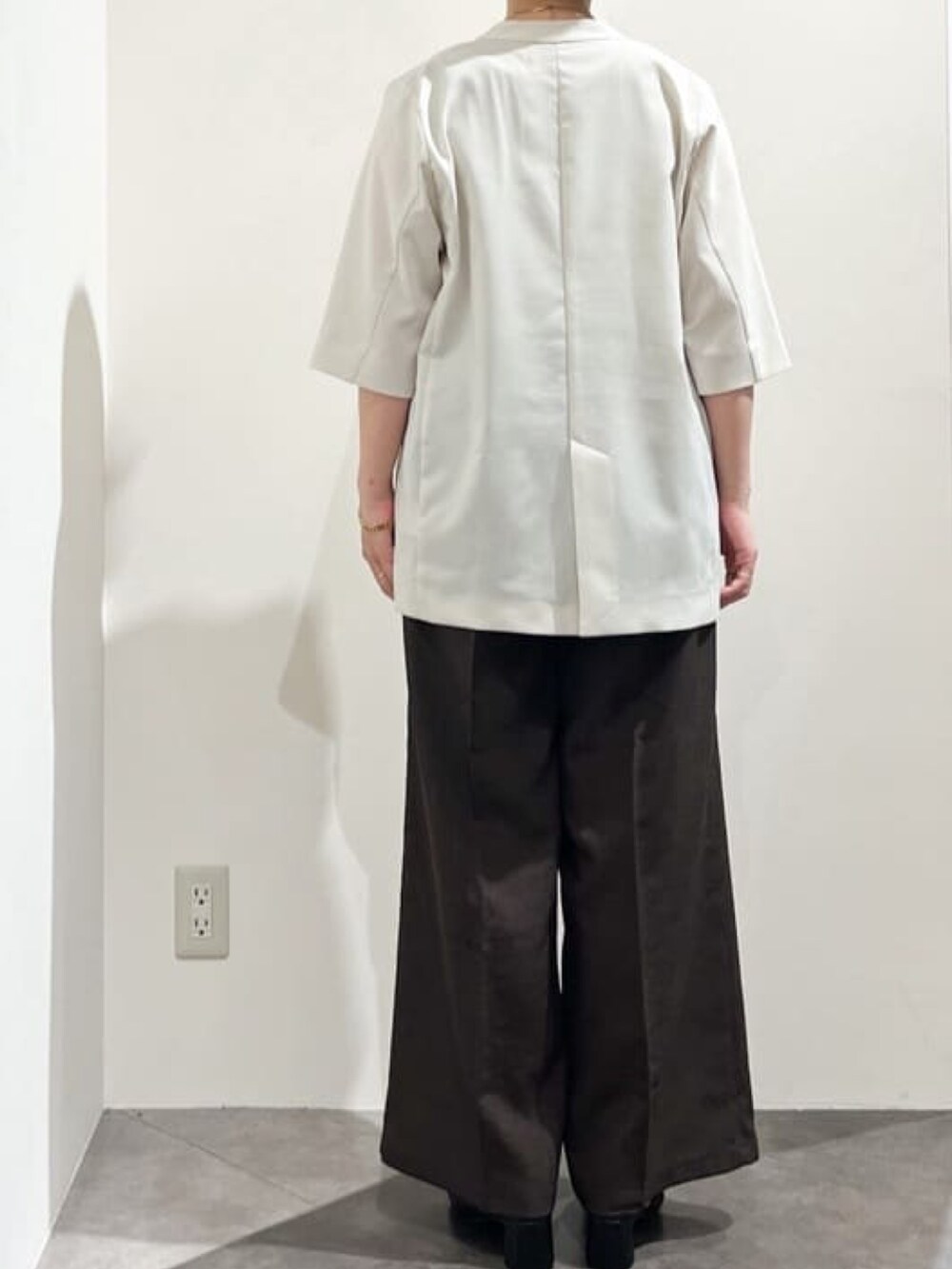 ベージュ系のノーカラージャケット、ベージュ系のニット/セーター、ブラック系のショルダーバッグを着用したレディースの夏コーディネートの4枚目の写真