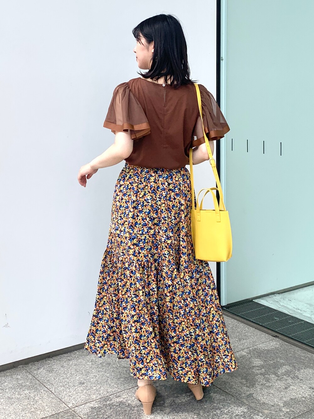 ブラウン系のTシャツ/カットソー、オレンジ系のスカート、イエロー系のショルダーバッグを着用したレディースの夏コーディネートの3枚目の写真