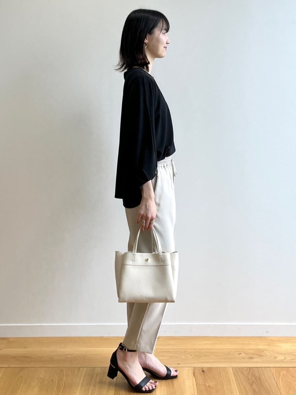 ブラック系のTシャツ/カットソー、ベージュ系のその他パンツ、ブラック系のサンダルを着用したレディースの春コーディネートの2枚目の写真