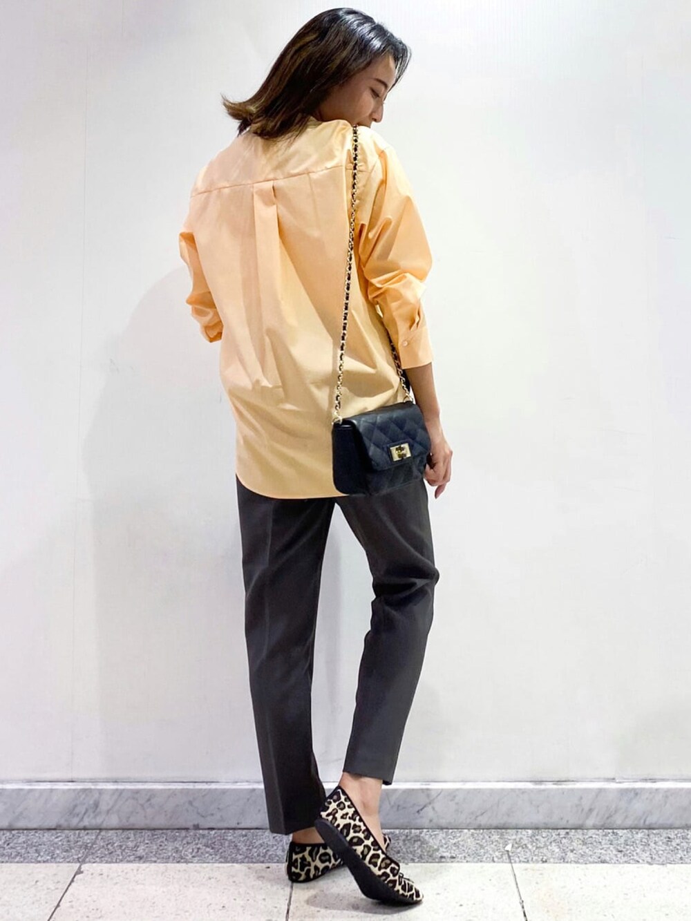 オレンジ系のシャツ/ブラウス、グレー系のその他パンツ、ブラック系のショルダーバッグを着用したレディースの秋コーディネートの2枚目の写真