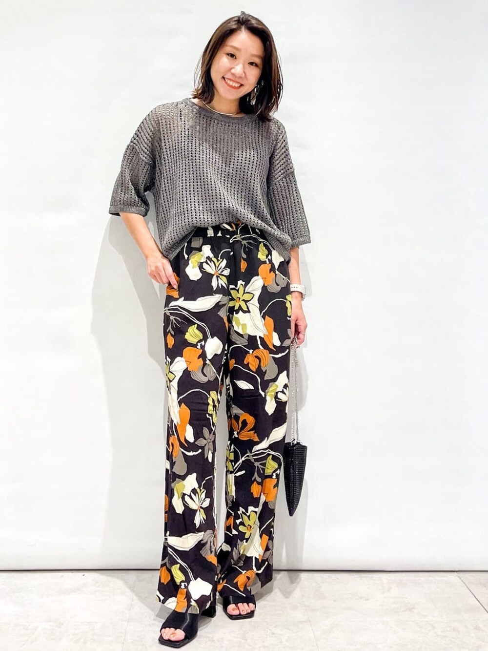 シルバー系のニット/セーター、ブラウン系のその他パンツ、ブラック系のショルダーバッグを着用したレディースの夏コーディネートの3枚目の写真