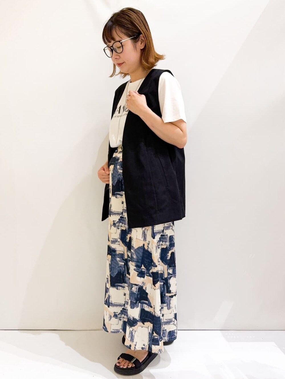 ホワイト系のTシャツ/カットソー、ブラック系のベスト、シルバー系のトートバッグを着用したレディースの夏コーディネートの2枚目の写真