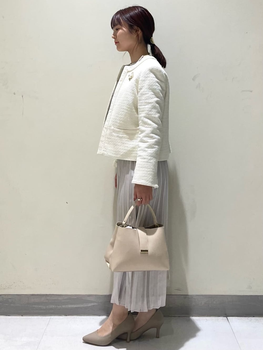 ホワイト系のノーカラージャケット、ベージュ系のワンピース、ベージュ系のショルダーバッグを着用したレディースの冬コーディネートの2枚目の写真