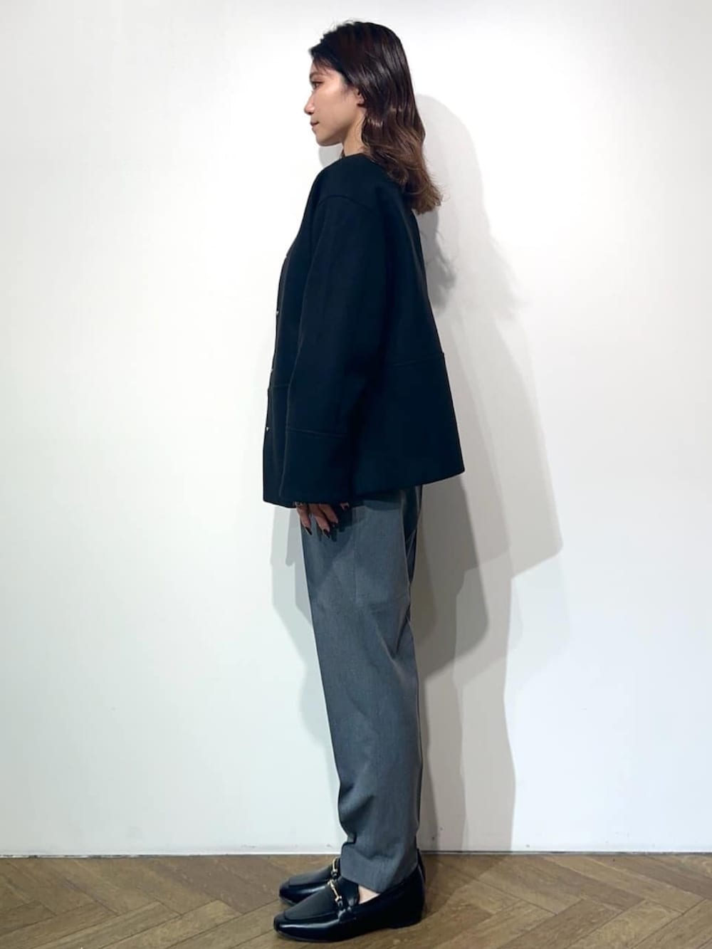 グレー系のその他パンツ、ブラック系のドレスシューズ、ブラック系のノーカラーコートを着用したレディースの冬コーディネートの3枚目の写真