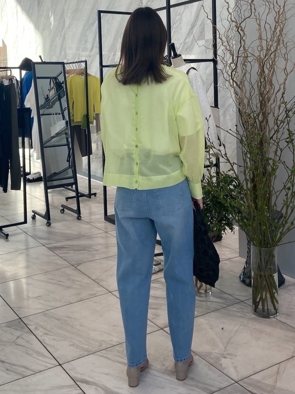 グリーン系のニット/セーター、ブルー系のデニムパンツ、ベージュ系のサンダルを着用したレディースの春コーディネートの4枚目の写真