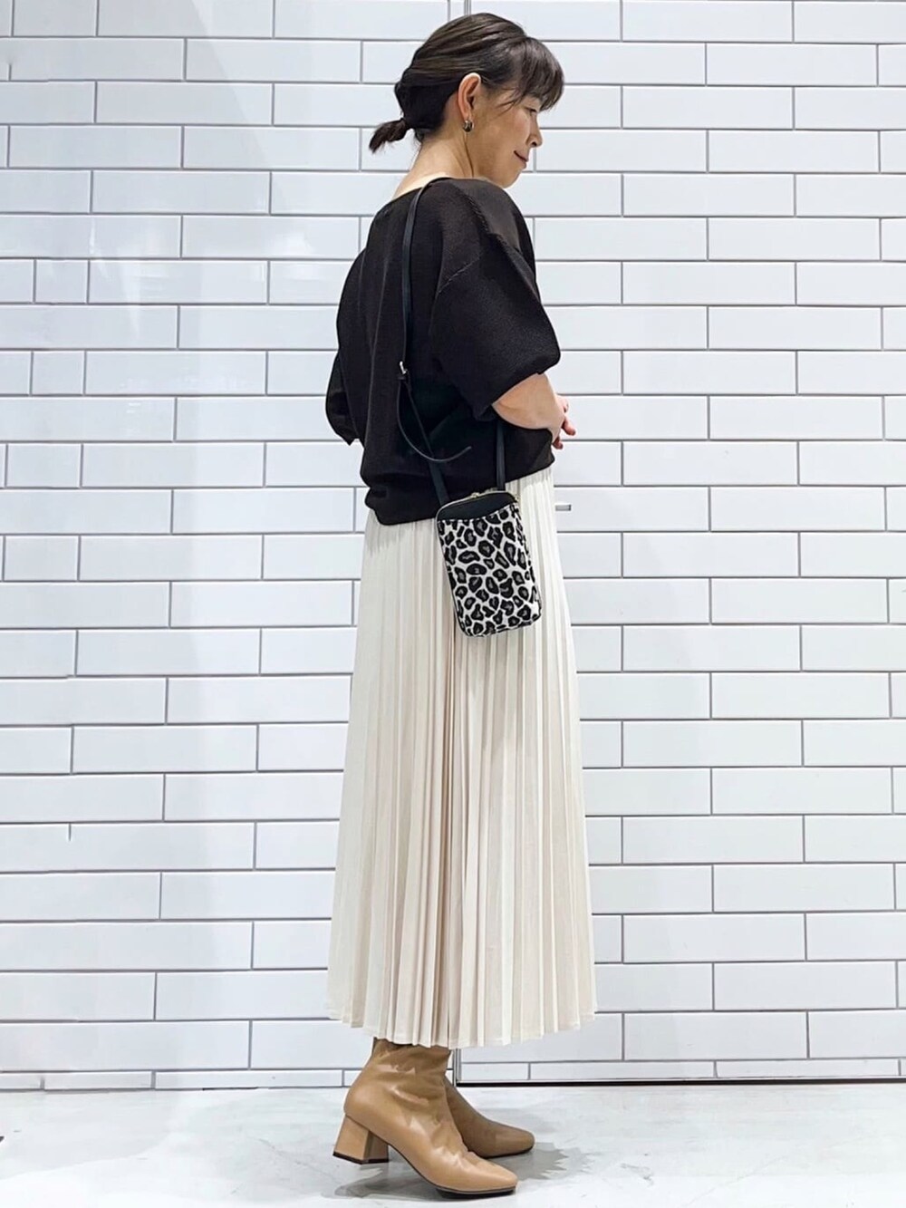 ブラウン系のニット/セーター、ホワイト系のスカート、ブラック系のショルダーバッグを着用したレディースの秋コーディネートの2枚目の写真