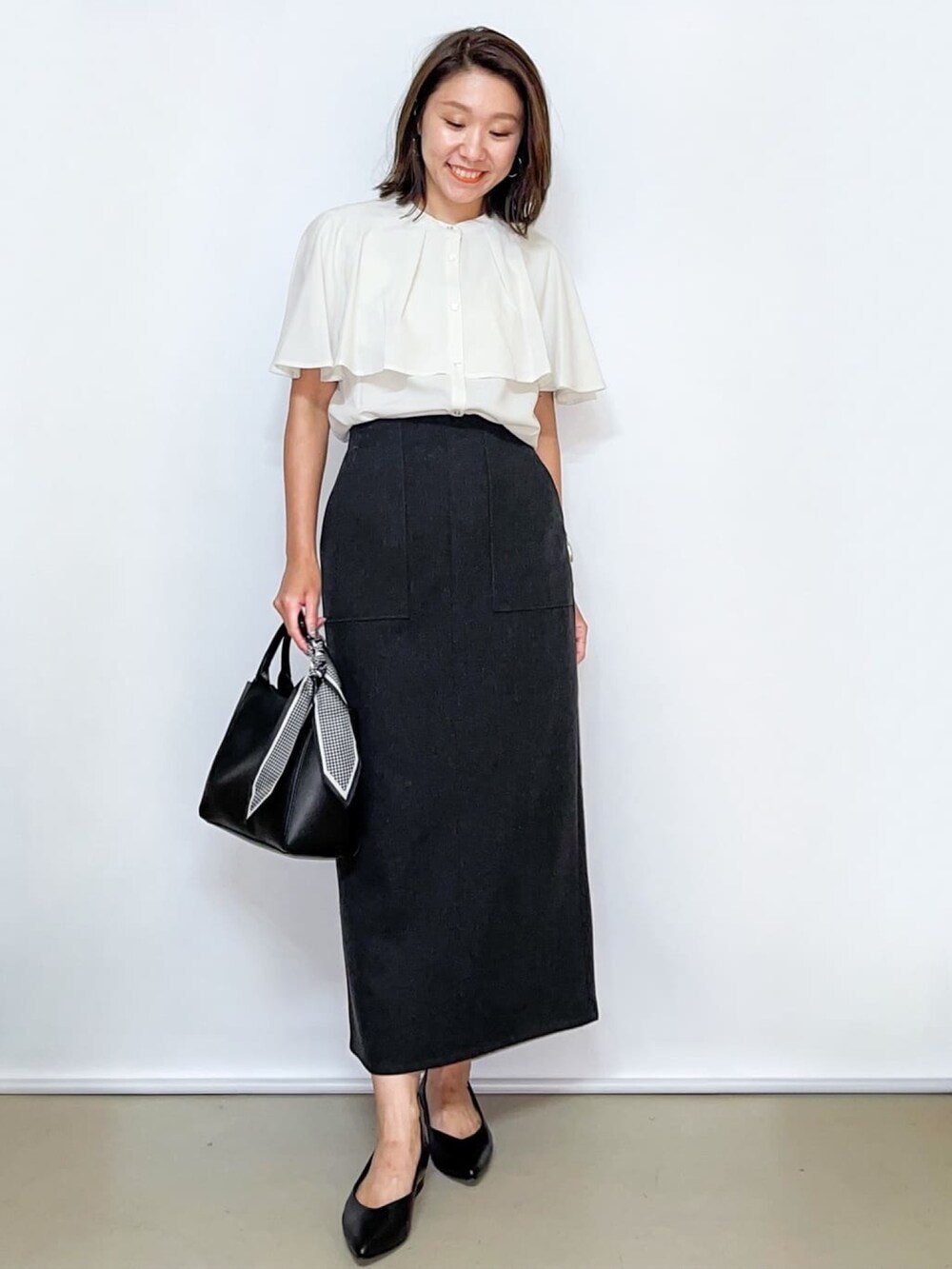 ホワイト系のシャツ/ブラウス、グレー系のスカート、ブラック系のトートバッグを着用したレディースの夏コーディネートの3枚目の写真