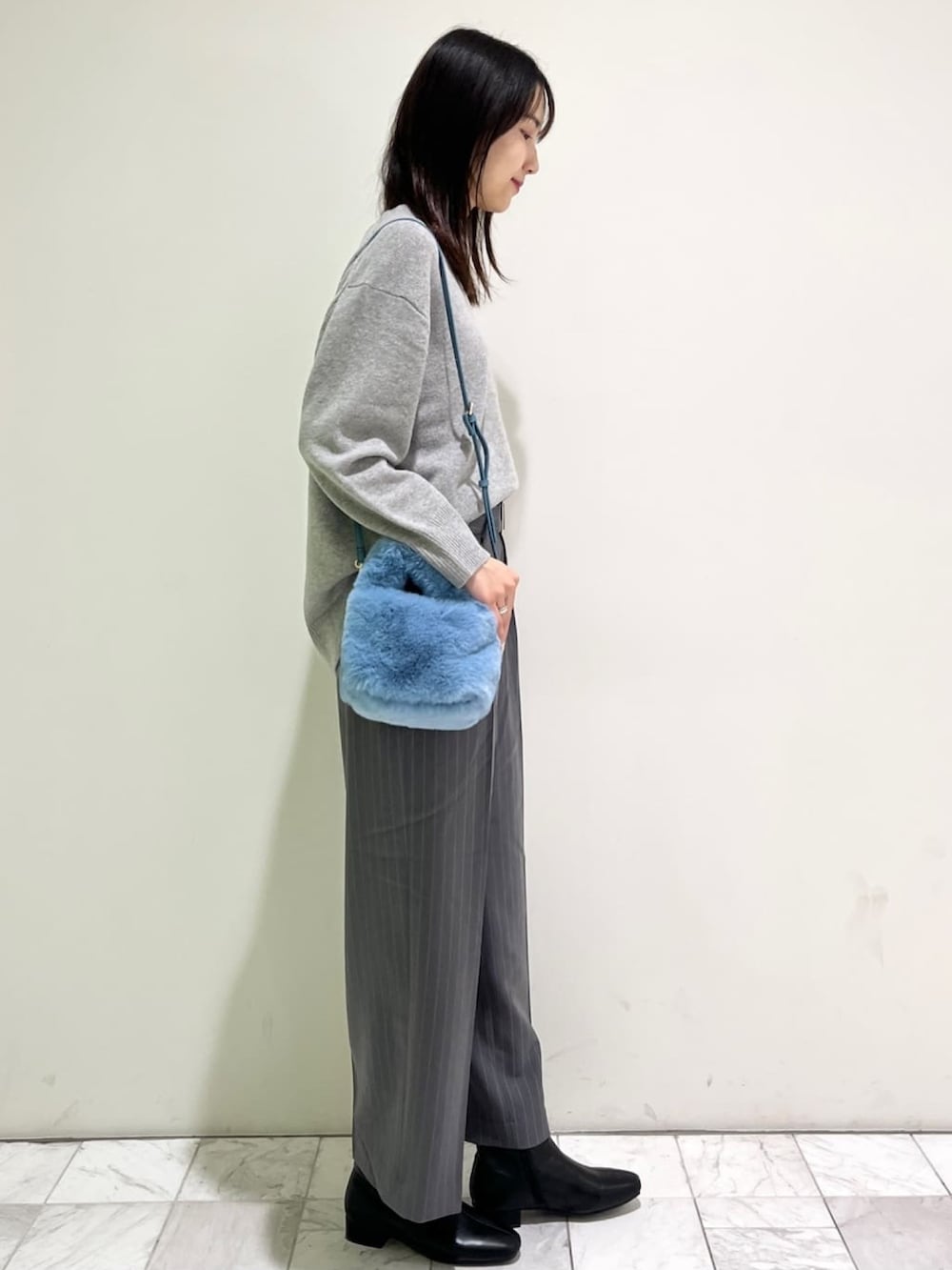 グレー系のニット/セーター、グレー系のその他パンツ、ブルー系のショルダーバッグを着用したレディースの冬コーディネートの3枚目の写真