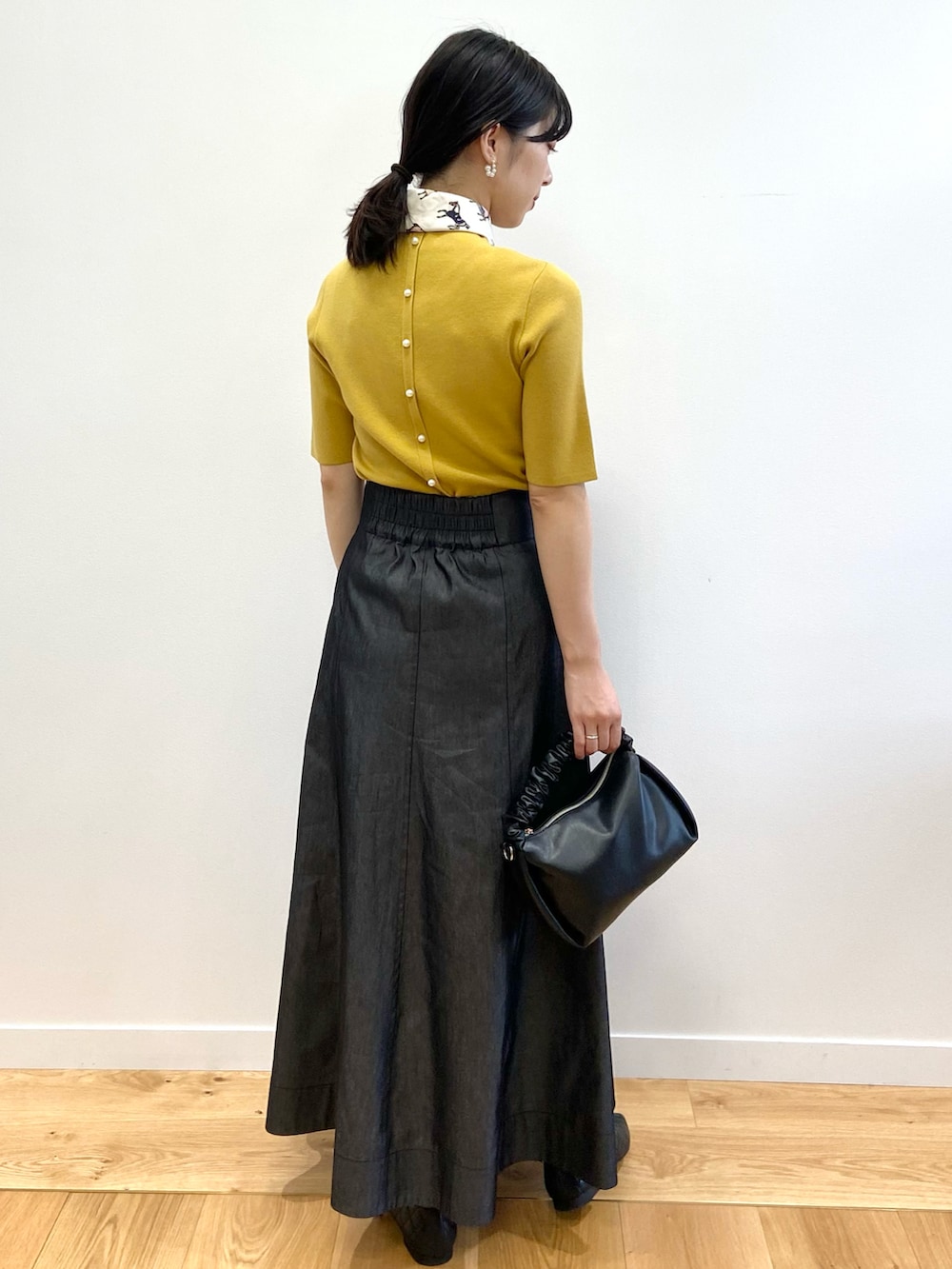 イエロー系のニット/セーター、その他のスカート、ブラック系のショルダーバッグを着用したレディースの夏コーディネートの4枚目の写真