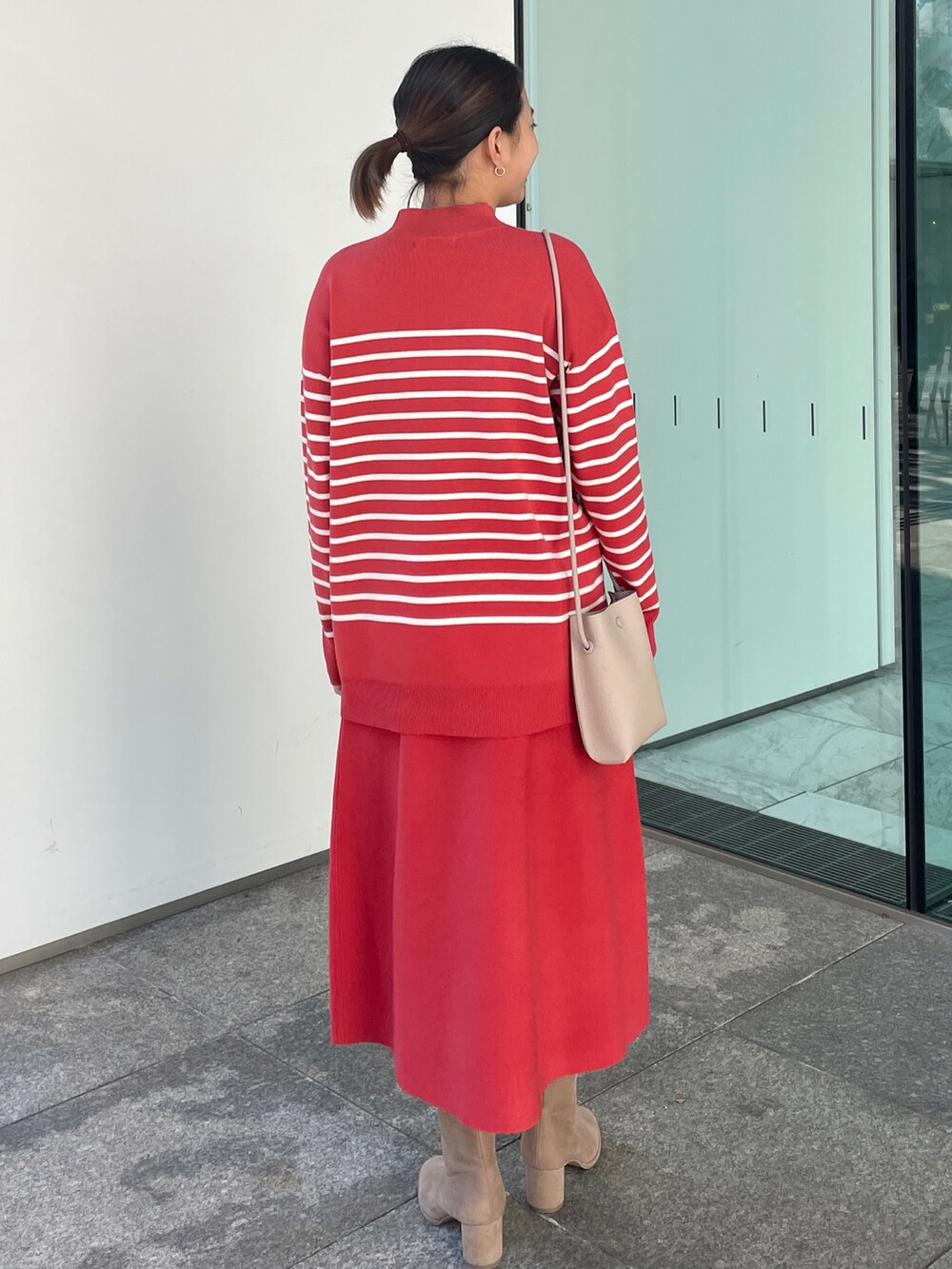 レッド系のニット/セーター、レッド系のスカート、ベージュ系のブーツを着用したレディースの冬コーディネートの3枚目の写真