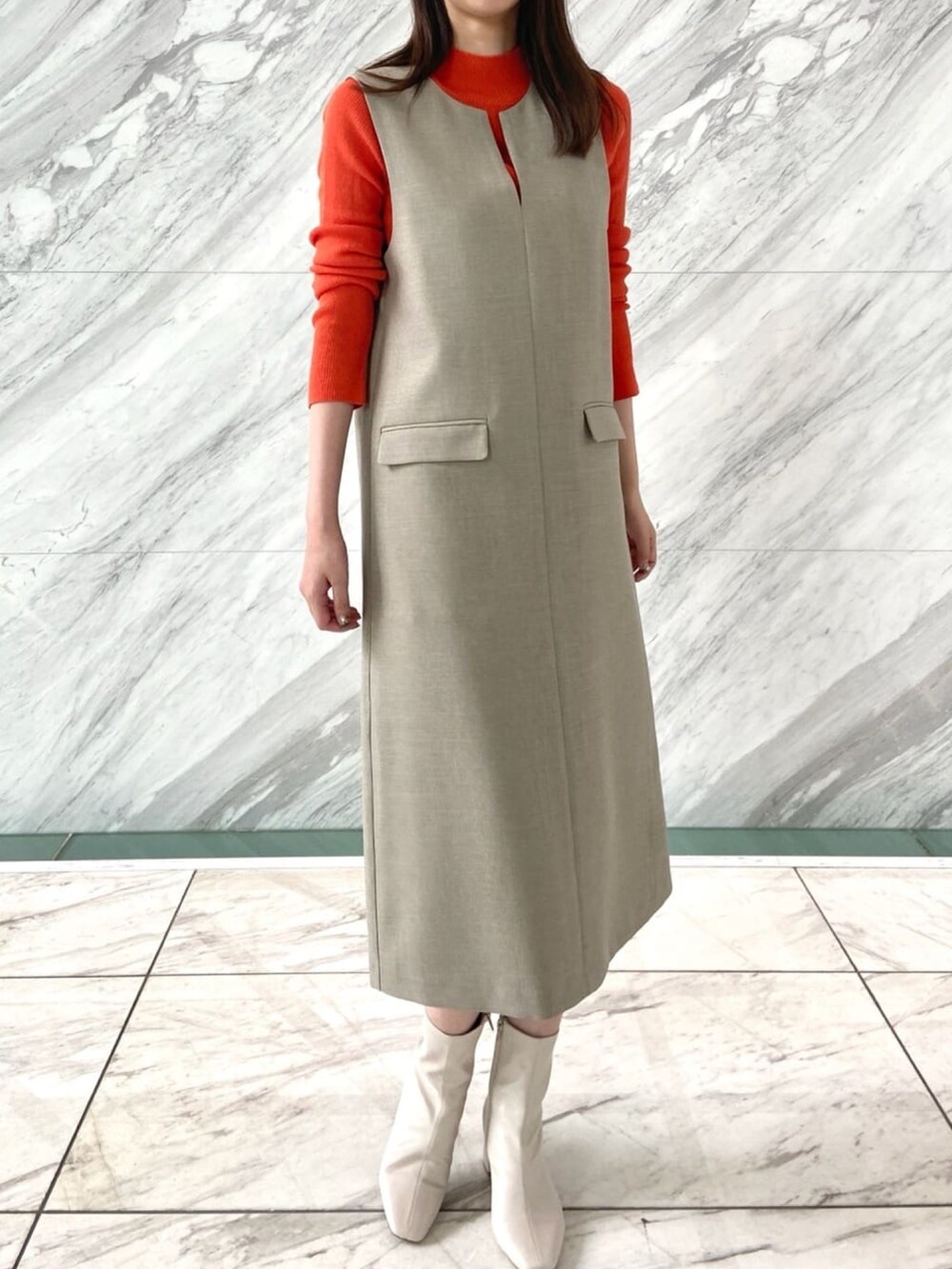 オレンジ系のニット/セーター、ベージュ系のワンピース、ホワイト系のブーツを着用したレディースの秋コーディネートの9枚目の写真