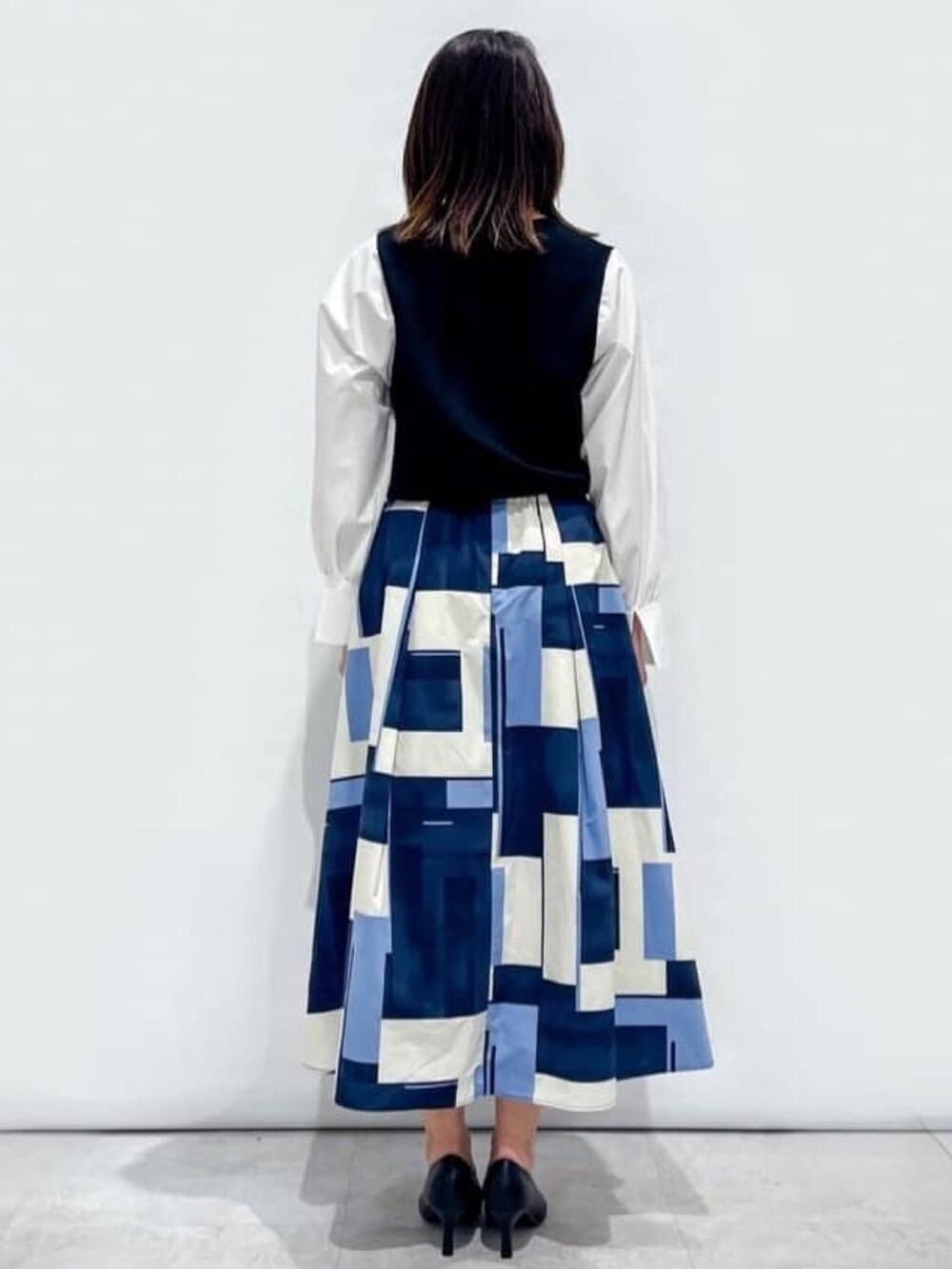 ブラック系のニット/セーター、ブルー系のスカート、ブラック系のショルダーバッグを着用したレディースの春コーディネートの3枚目の写真