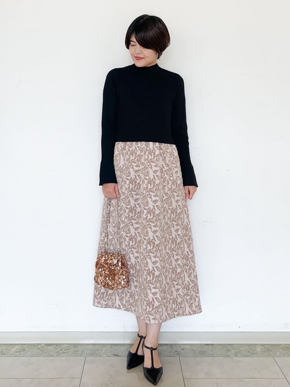 ベージュ系のワンピース、ブラウン系のショルダーバッグ、ブラック系のパンプスを着用したレディースの秋コーディネートの2枚目の写真