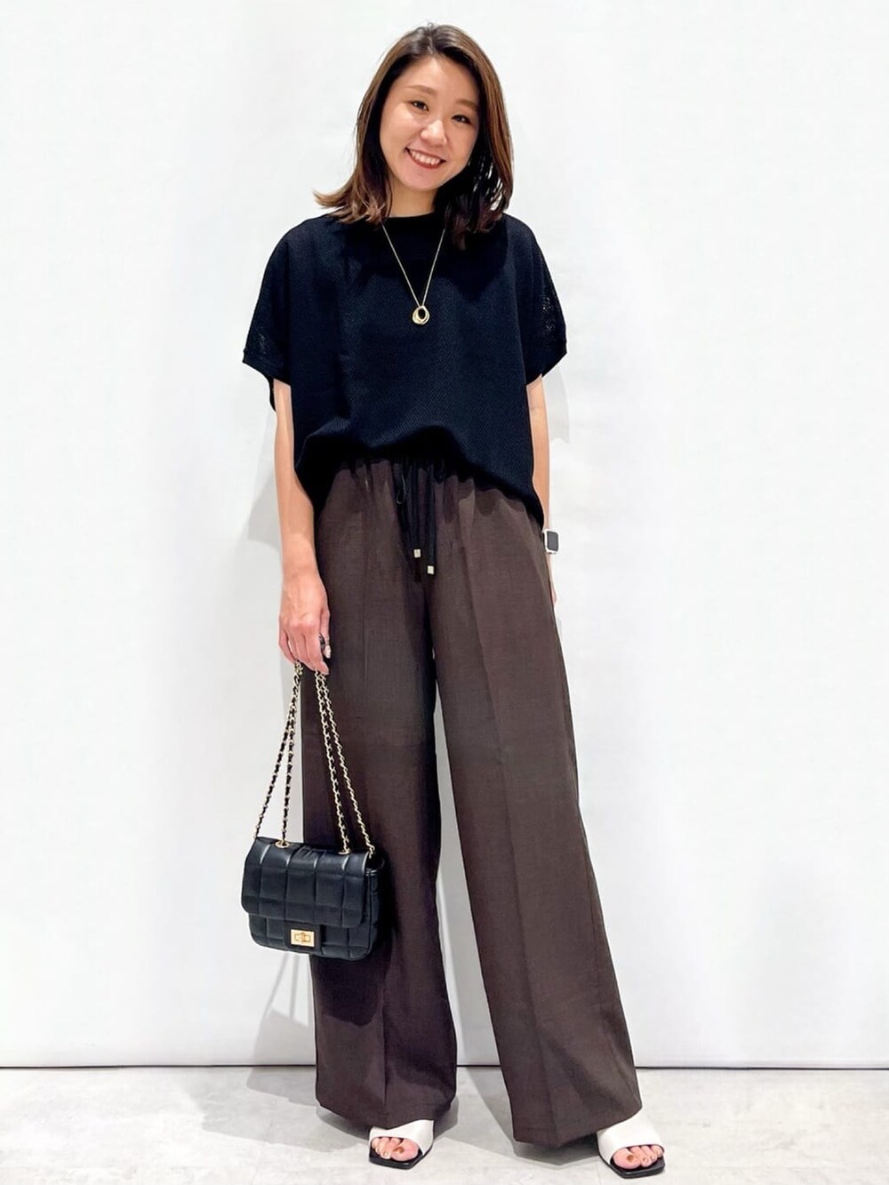 ブラウン系のその他パンツ、ホワイト系のサンダル、ブラック系のショルダーバッグを着用したレディースの夏コーディネートの3枚目の写真
