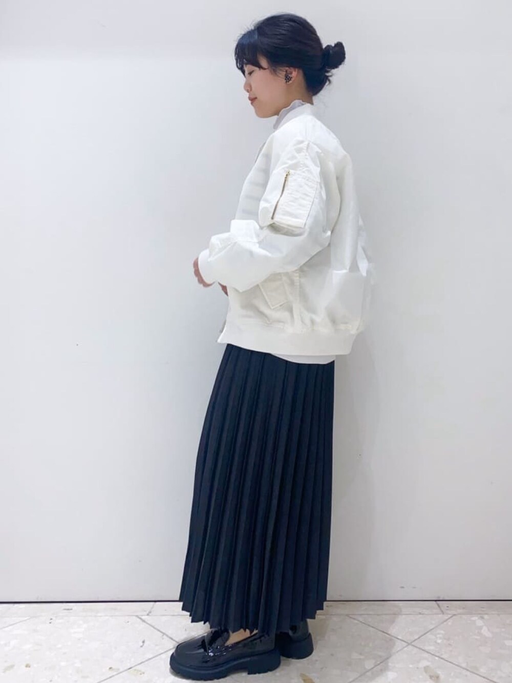 グレー系のスカート、ホワイト系のニット/セーター、ホワイト系のブルゾンを着用したレディースの冬コーディネートの2枚目の写真